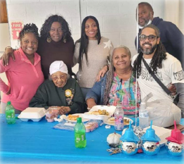 Six people huddle around Lillian Boyd and smile for a picture.
