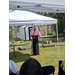  A person speaking at a podium under a tent. 