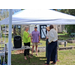  Three people stand and talk under a tent. 