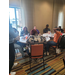  A table full of people listen to someone speak. 