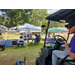  A man in a golf cart looks out at tables and booths. 