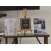  A display is set up on a table with flyers and a plaque. 