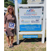  A woman holding a fan that says Realtor next to a sign for the Neighborhood Revitalization program. 