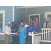  Fifteen people standing on a porch cutting a big ribbon. 