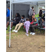  A group of people and kids sitting under a tent. 